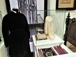 1958 m. muziejui perduoti eksponatai: M. Reizgienės juodas aksominis švarkelis, delmonas, šimtaraštė juostelė. MLIM ekspozicija / A. Kavaliauskienės nuotr.